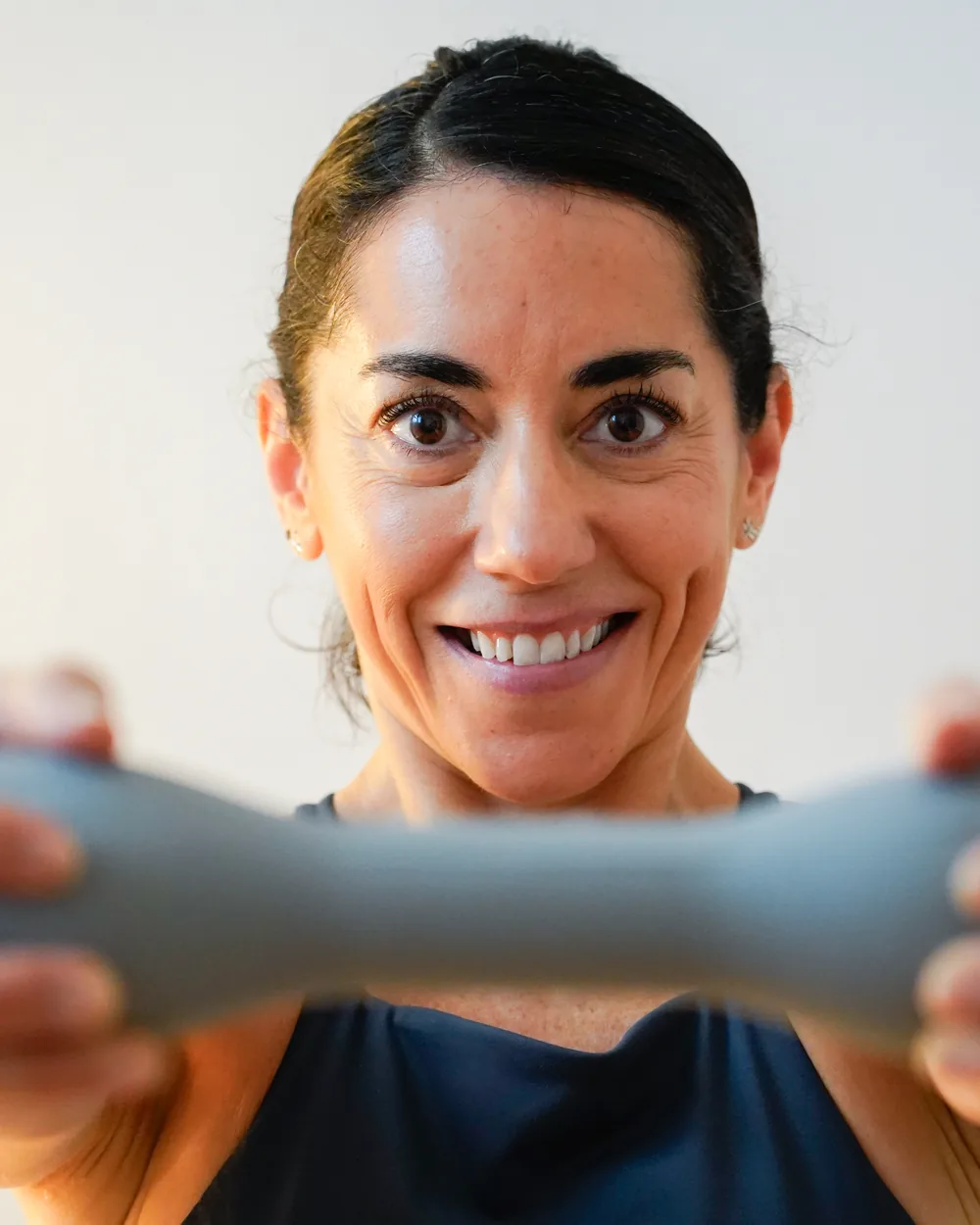 Belén sonriendo a cámara mientras sostiene una toning bar con las dos manos